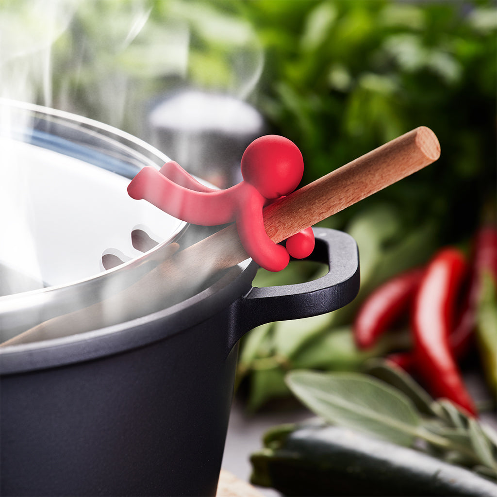 Silicone Hug Doug figurine holding a spoon on the pot edge